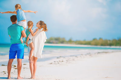 Rear view of cheerful family standing on beach