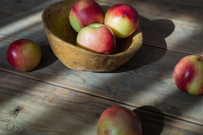 Red and green mini nectarine in a wooden bowl.