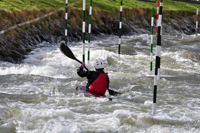 Rear view of men performing river rafting