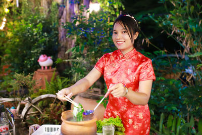 Portrait of smiling young woman standing against plants