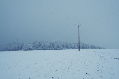 Snow covered field against clear sky