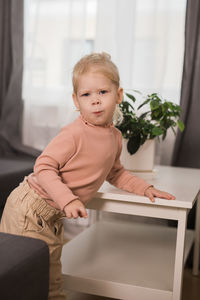 Portrait of cute baby boy sitting on sofa at home