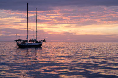 Boat sailing in sea at sunset