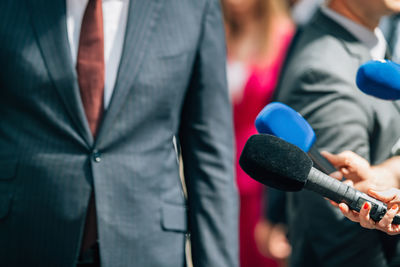 Journalists holding microphone, interviewing politician.