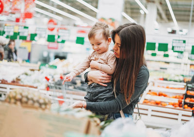 Young woman with baby boy standing in supermarket