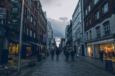 People walking on street amidst buildings in city