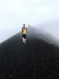 Rear view of people walking on mountain during foggy weather