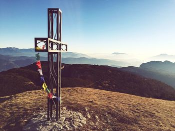 Metallic cross on mountain against sky