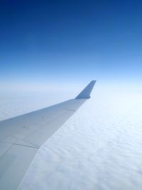 Close-up of airplane wing against clear blue sky