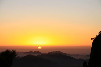 Scenic view of silhouette mountains against orange sky