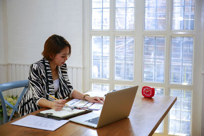 Woman using mobile phone while sitting on table