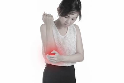 Digital composite image of young woman with elbow pain standing against white background