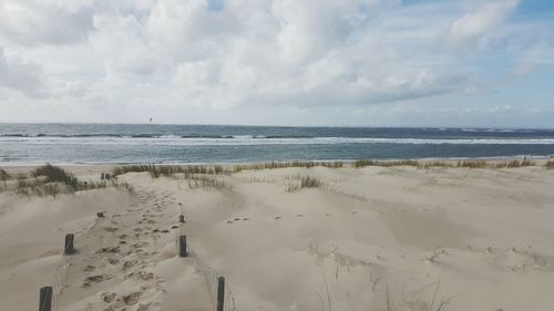 Scenic view of sandy beach against cloudy sky