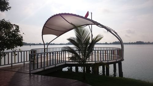 Railing by lake against sky