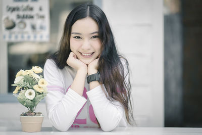 Portrait of smiling young woman sitting at table in city