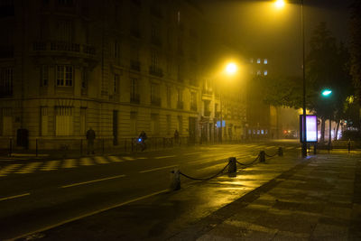 Road against illuminated building at night