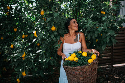 Young woman standing by tree in basket