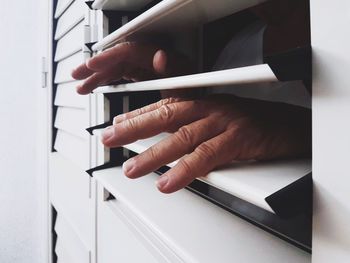 Close-up of woman reaching through blinds