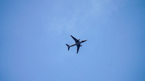 Low angle view of airplane flying against clear blue sky