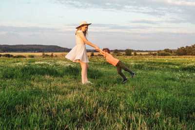 Woman with umbrella on field against sky