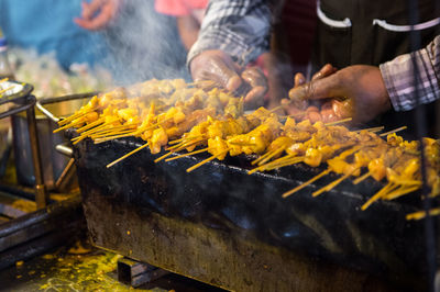 Cropped hands of chef roasting meat on barbecue grill in commercial kitchen