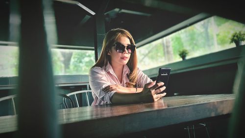 Young woman using phone while sitting outdoors