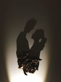 Silhouette people holding illuminated light against dark background