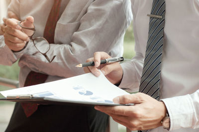 Midsection of man holding paper
