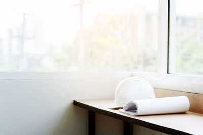 Blueprints with hardhat on wooden table by window