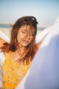 Portrait of young woman standing against sky