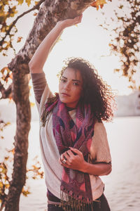 Young woman standing on tree against sky