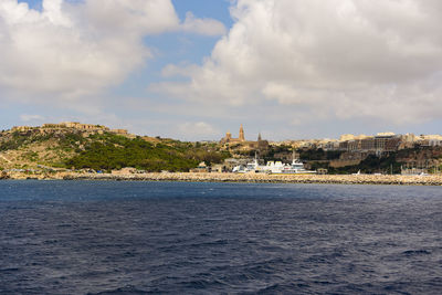 Sea by buildings against sky in city