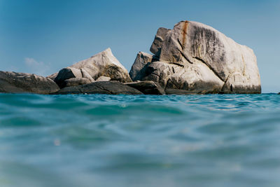 Rock formations in sea against blue sky