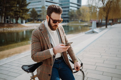 Creative director using mobile phone. man standing next to bicycle with smartphone.