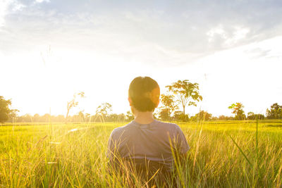 Rear view of man standing on field against sky