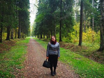 Young woman standing amidst trees in forest