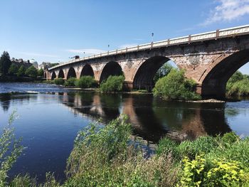 Arch bridge over river against sky