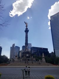 Statue in city against sky