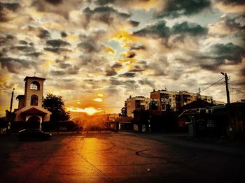 Street amidst buildings against sky during sunset