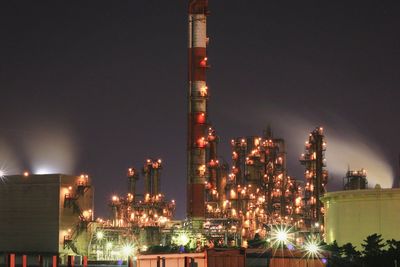 Illuminated factory against sky at night