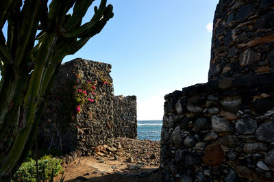 Stone wall by sea against clear sky