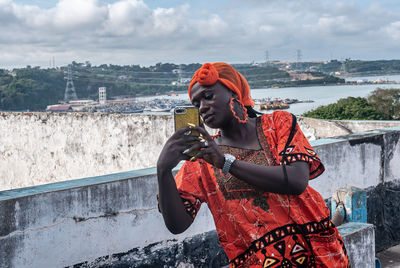 African woman photographing while standing outdoors