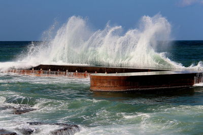 Waves splashing on sea against sky