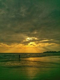 Scenic view of sea against cloudy sky during sunset