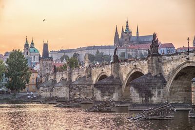 Arch bridge over river against buildings in city