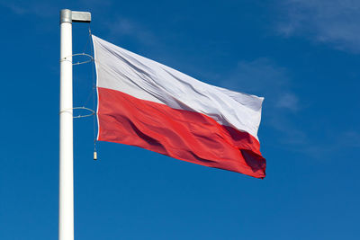 Low angle view of flag against blue sky