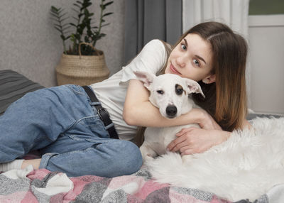 Girl with dog sitting on bed at home
