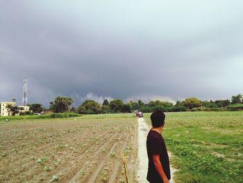 Rear view of man photographing on field against sky