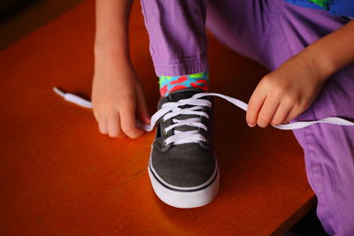 Midsection of girl tying shoelace at home