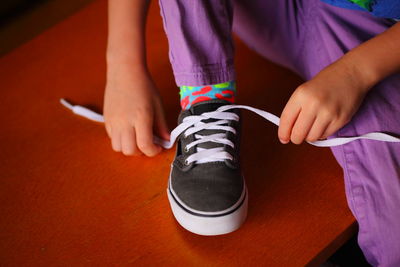 Midsection of girl tying shoelace at home